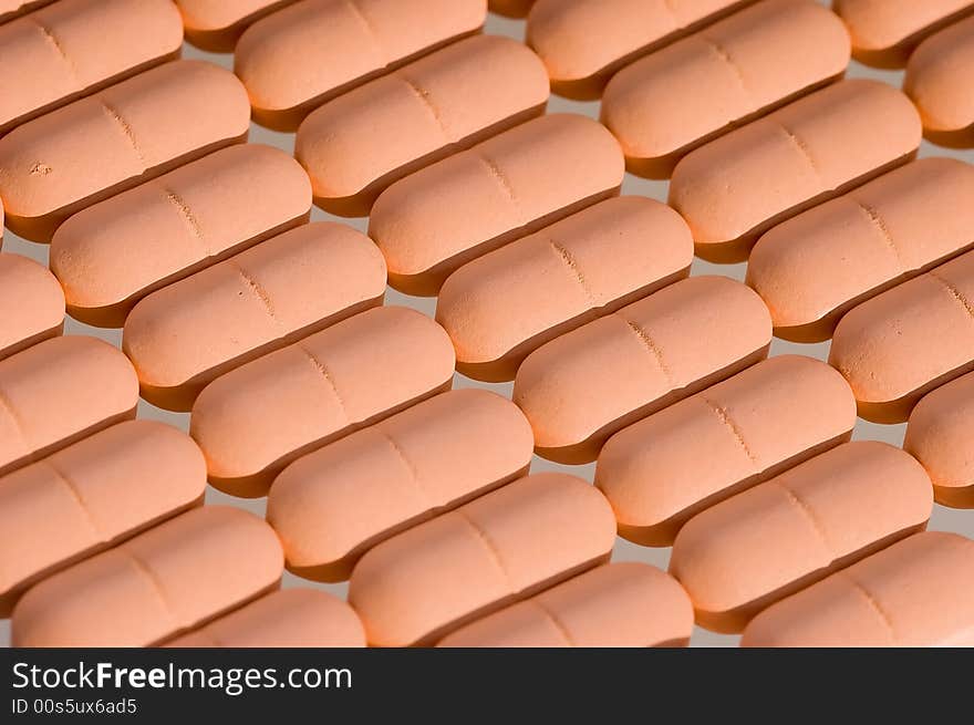 Rows of pink pills over white. Macro. Close-up