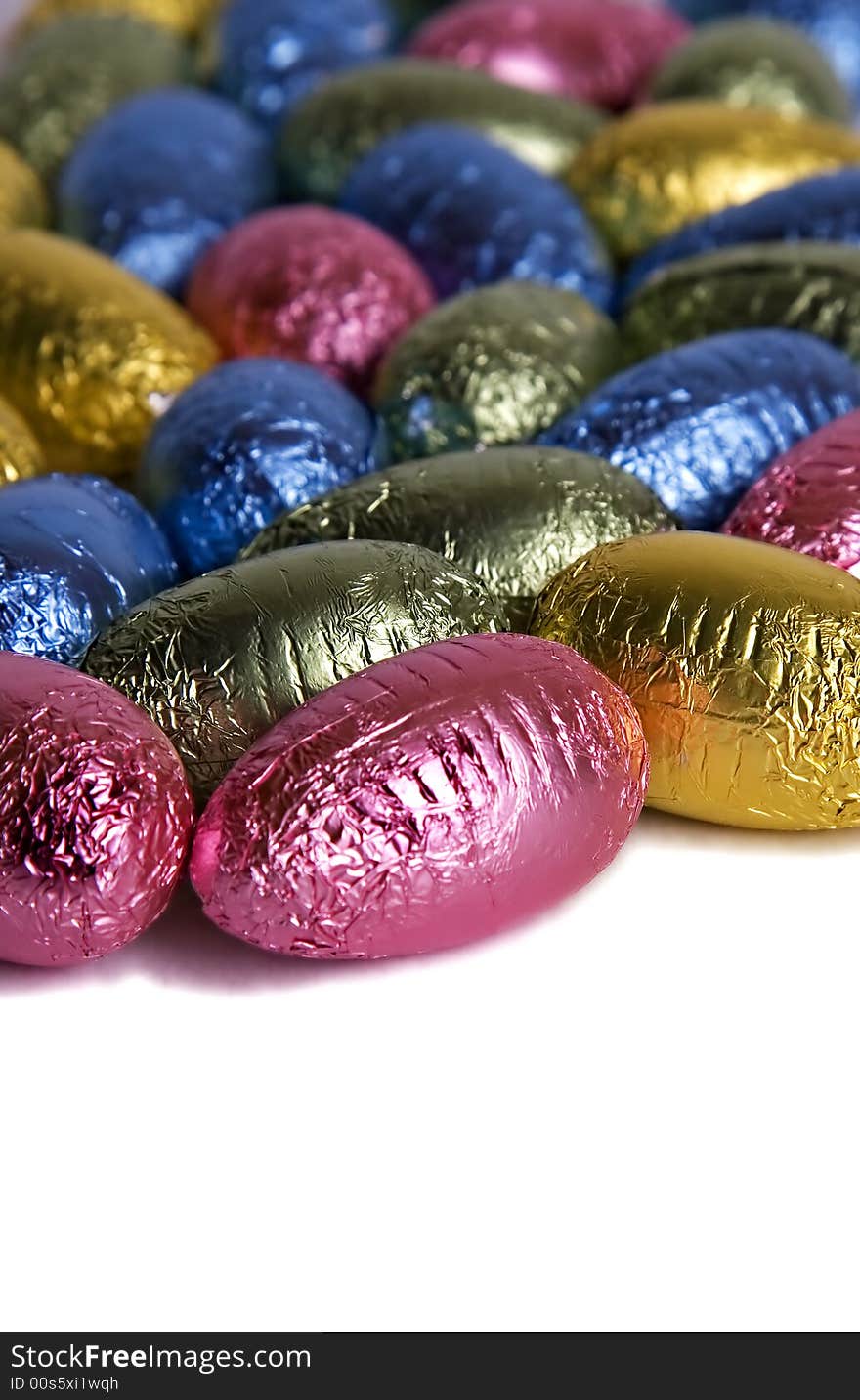 A large number of different color chocolate easter eggs on a white background. A large number of different color chocolate easter eggs on a white background