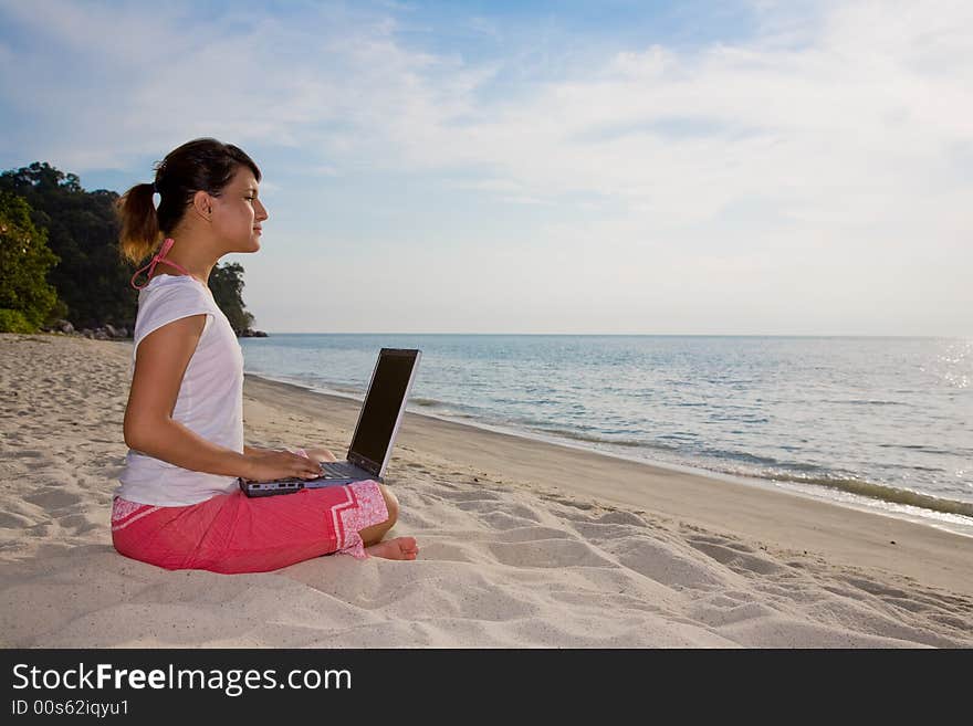 Young woman working on her laptop facing a beautiful beach. Young woman working on her laptop facing a beautiful beach
