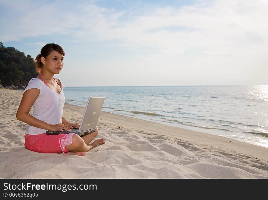 Woman working on her laptop  on a beautiful beach. Woman working on her laptop  on a beautiful beach