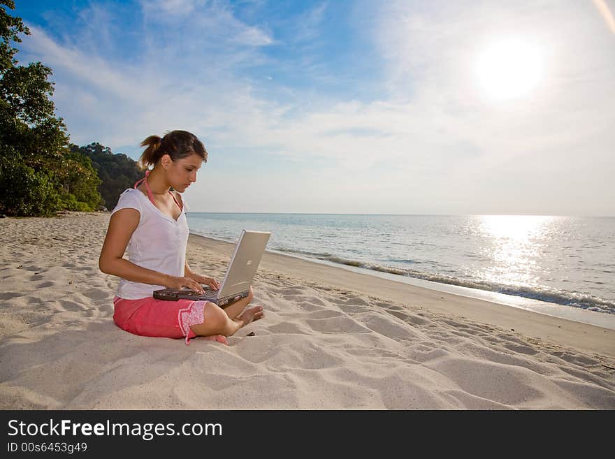 Woman working on her laptop on a beautiful beach. Woman working on her laptop on a beautiful beach