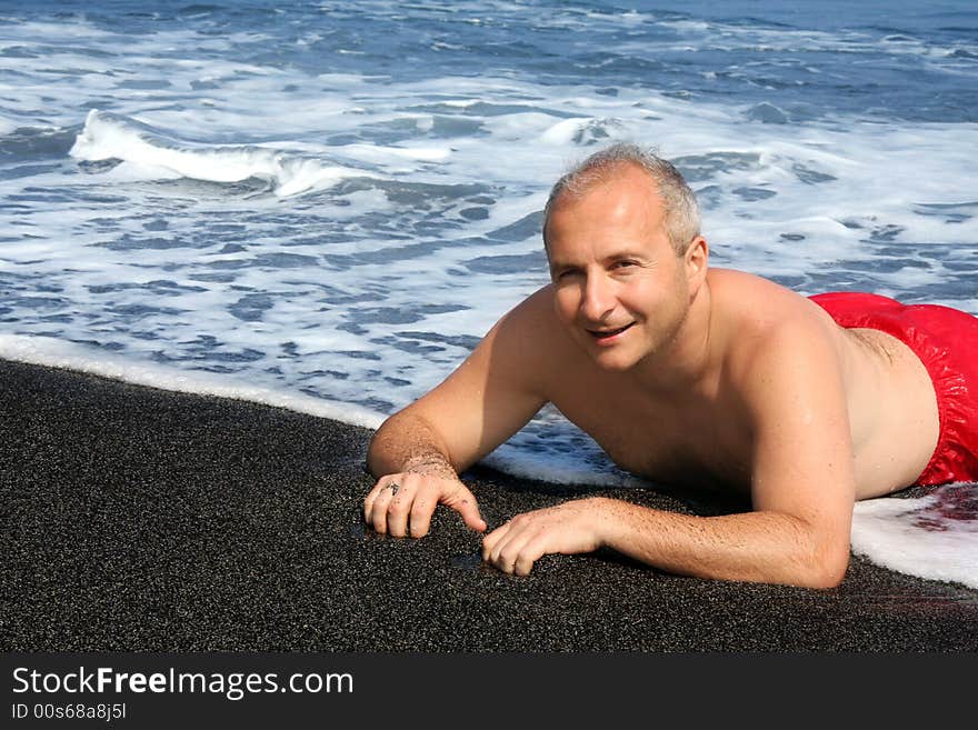 Mature man on a black sand beach on Big Island, Hawaii