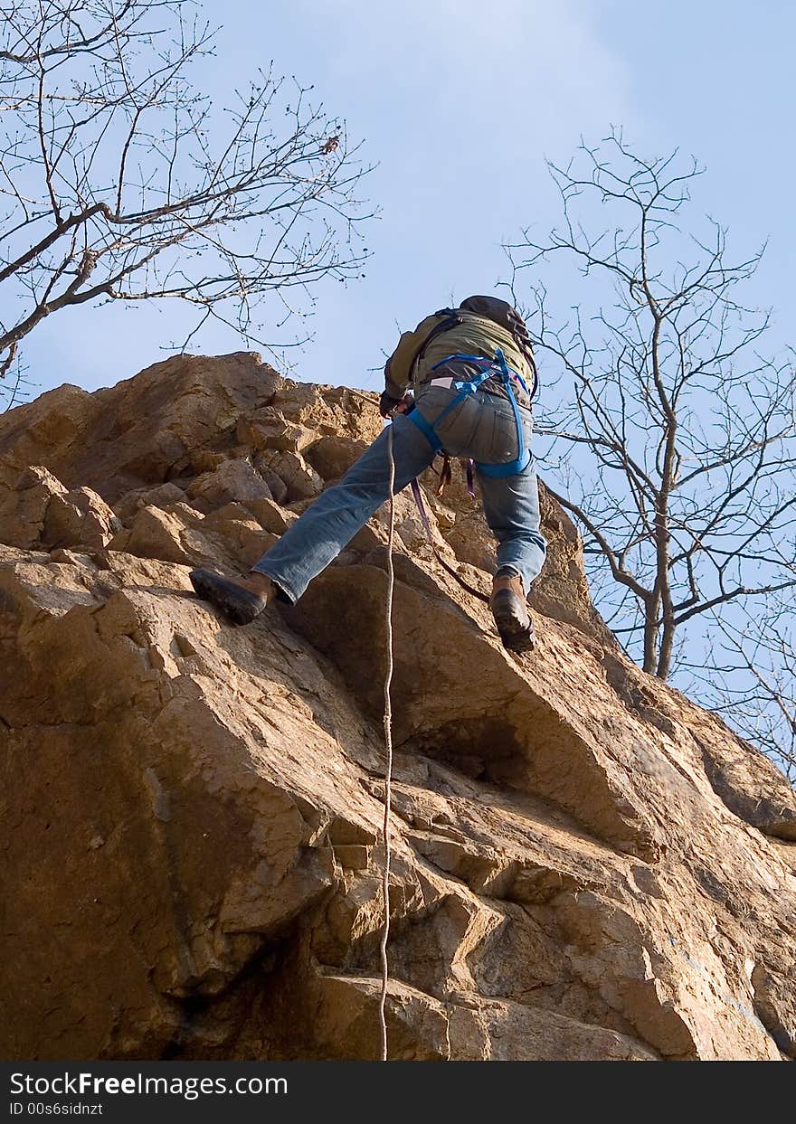 Climber hanging on the rope on the rock against blue sky. Climber hanging on the rope on the rock against blue sky