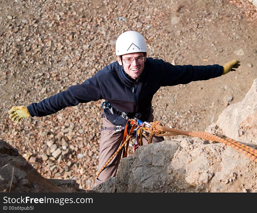 Climber hanging on the rock with arms wide open