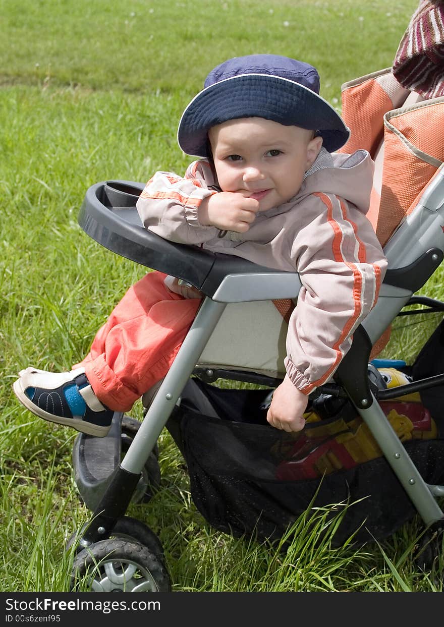 Kid walking in the stroller on the spring green meadow. Kid walking in the stroller on the spring green meadow