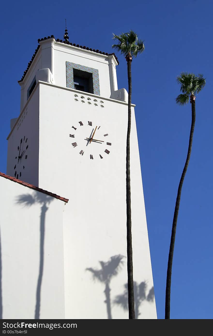 Architectural detail of Union Station's Spanish style clock tower with two palm trees against blue sky. Architectural detail of Union Station's Spanish style clock tower with two palm trees against blue sky