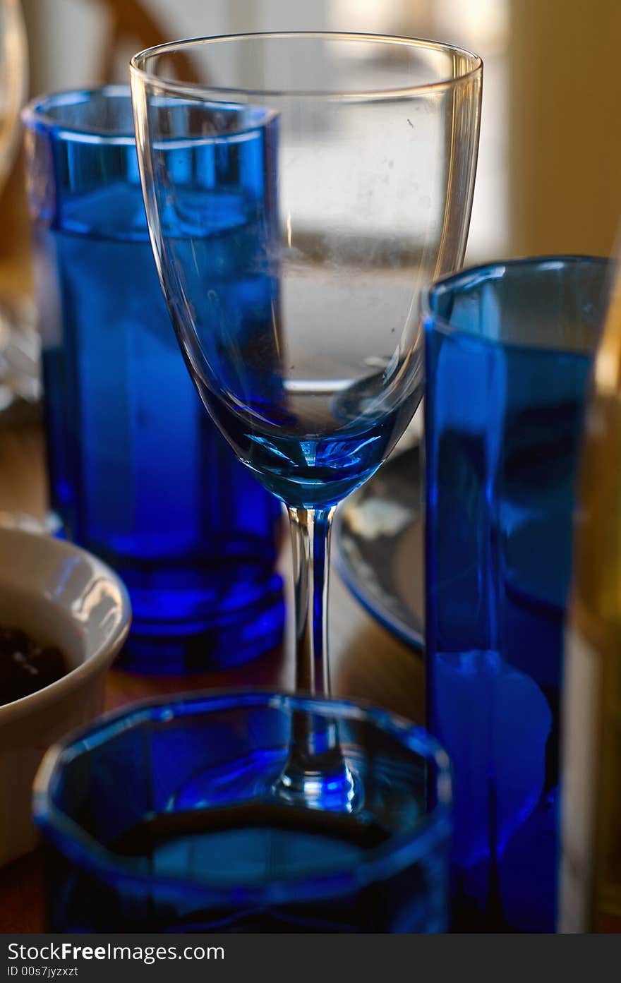 Wineglasses and blue glassware adorn this tabletop, waiting for people. Wineglasses and blue glassware adorn this tabletop, waiting for people