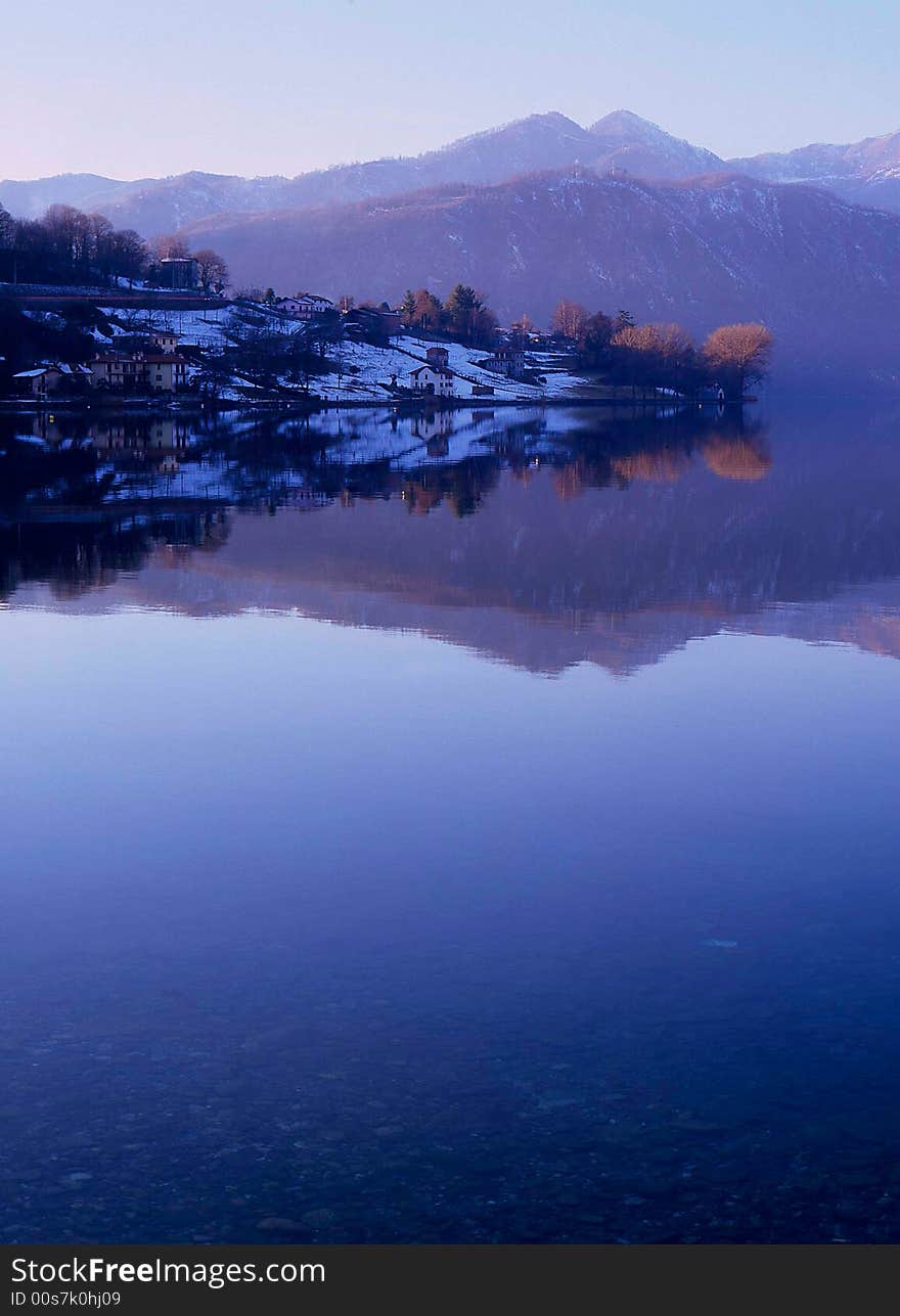 Lake landscape with snow, blue sky and blue water, huoses and trees. Lake landscape with snow, blue sky and blue water, huoses and trees