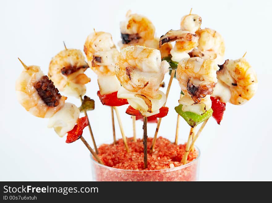 Prawns and octopus prepared at the plate on skewers