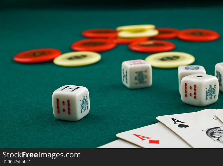 Dice, cards and chips on green carpet with selective focus