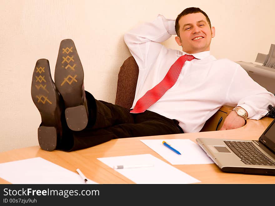 Young businessman relaxing at office with legs on table. Young businessman relaxing at office with legs on table