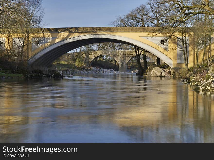 The medieval Devils bridge seen through the modern road gridge on the river Lune near Kirkby Lonsdale, Cumbria, UK. The medieval Devils bridge seen through the modern road gridge on the river Lune near Kirkby Lonsdale, Cumbria, UK