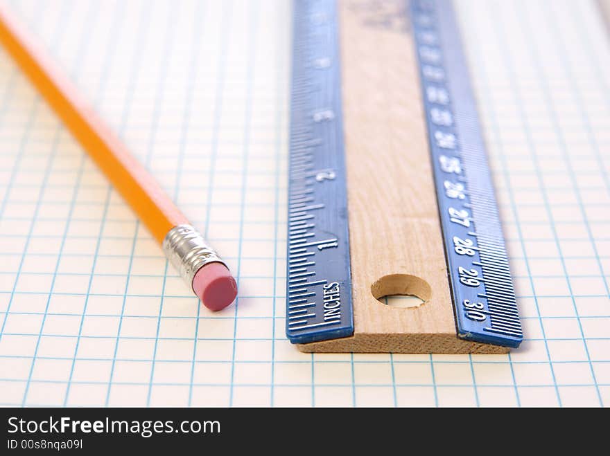 Wooden ruler and pencil on graph paper. Low depth