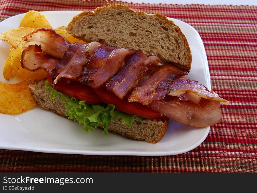 Bacon, Lettuce, and Tomato (BLT) on rustic whole grain loaf bread with chips. Bacon, Lettuce, and Tomato (BLT) on rustic whole grain loaf bread with chips.