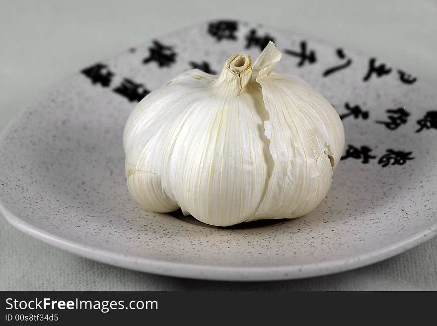 Isolated, white, fresh garlic on ceramic, small plate on white. Isolated, white, fresh garlic on ceramic, small plate on white