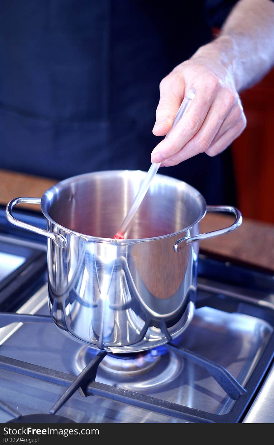 Chef keeps vigil over stainless steel pot on a gas stove. Chef keeps vigil over stainless steel pot on a gas stove.