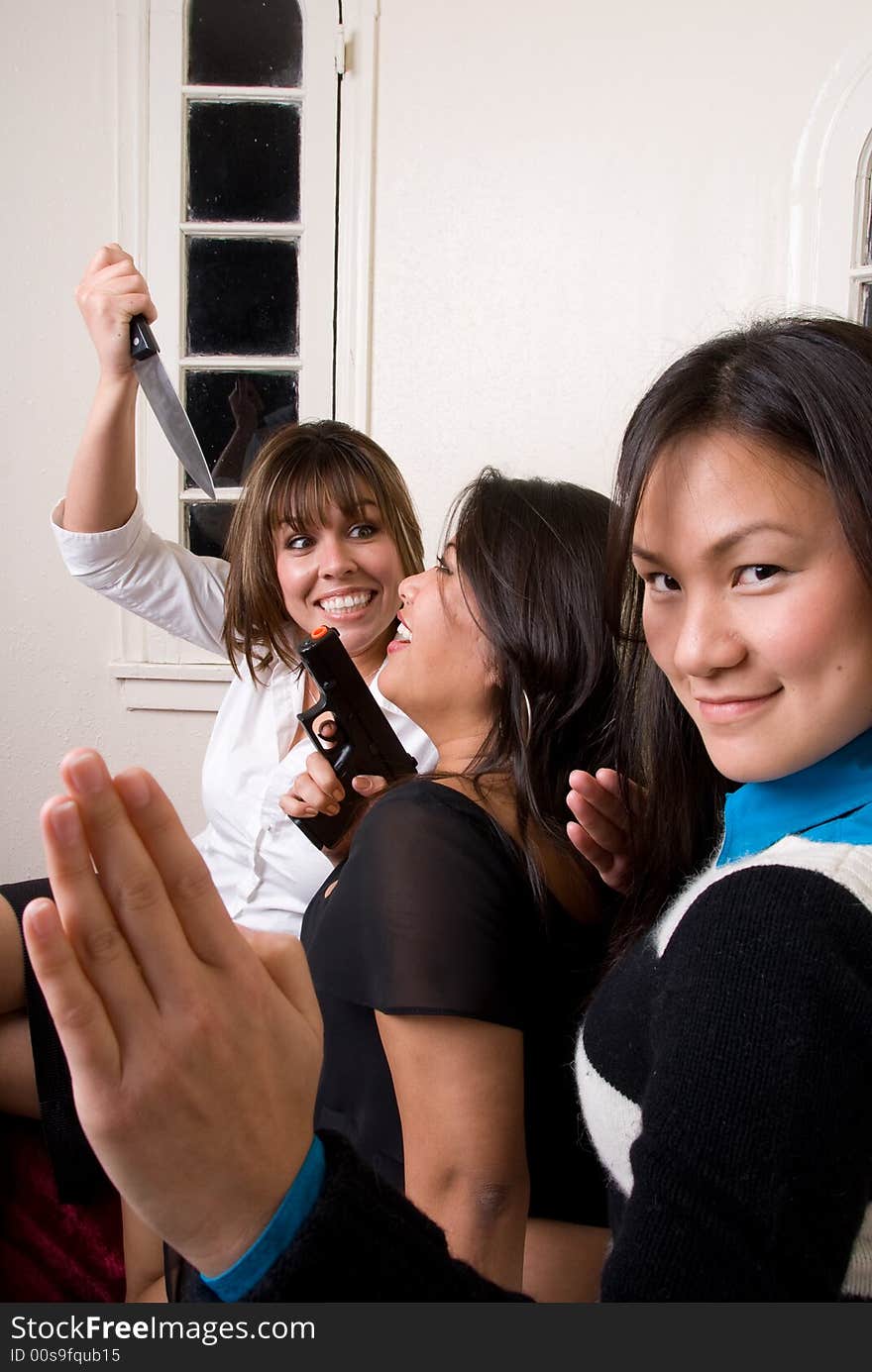 1 of the 3 females jokingly moves the knife towards her friend. 1 of the 3 females jokingly moves the knife towards her friend.