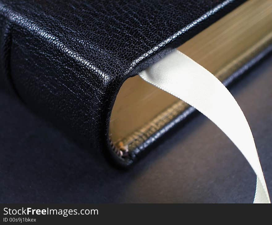 Fine leather bound book with gilded edge and silk bookmark on a black background. Fine leather bound book with gilded edge and silk bookmark on a black background