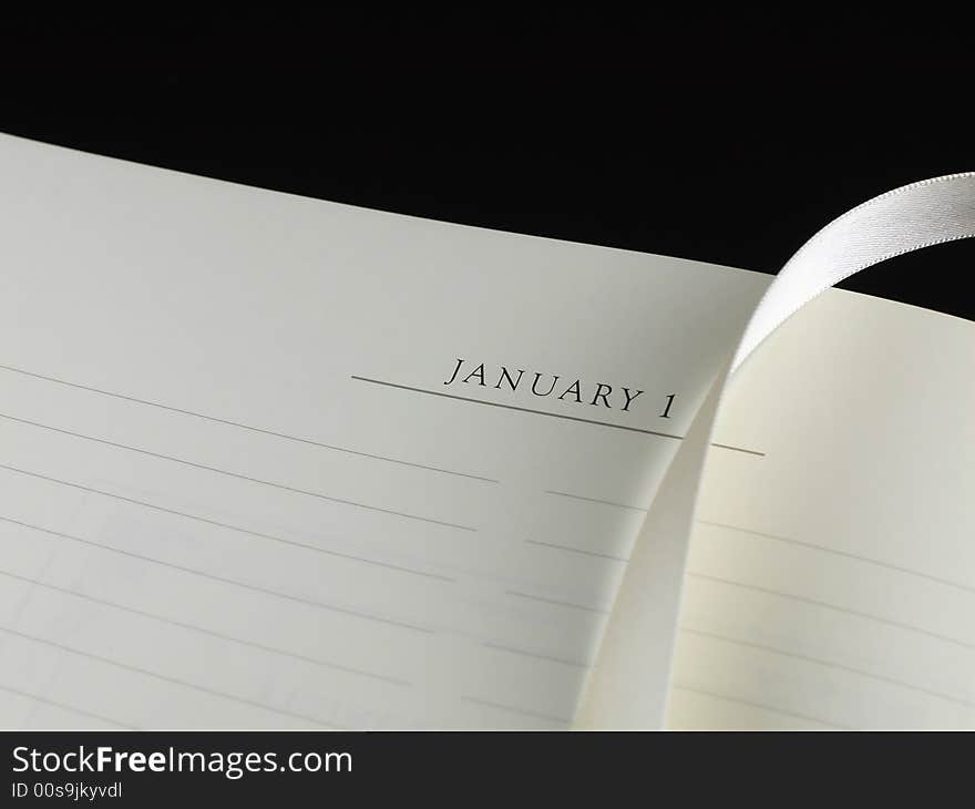 A blank sheet of paper with lines, a silk ribbon bookmark and a black pen against a black background. A blank sheet of paper with lines, a silk ribbon bookmark and a black pen against a black background