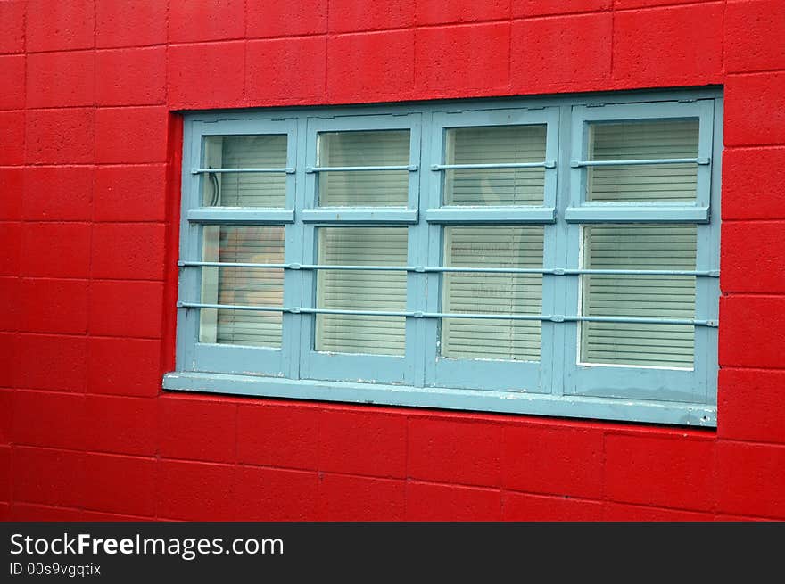 Blue wooden window frame against a red painted brick exterior. Blue wooden window frame against a red painted brick exterior