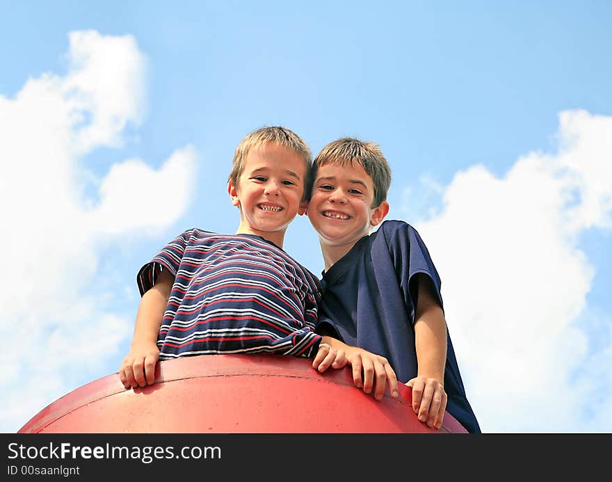 Brothers Playing on a Playground with the Blue Cloudy Sky in the Background