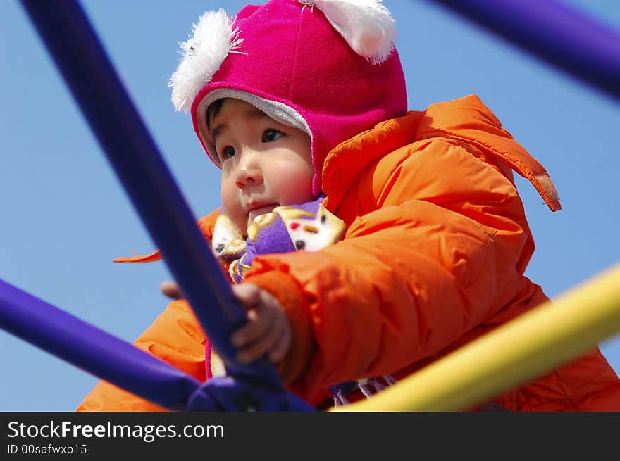 An Chinese little girl playing on climbing frame in winter