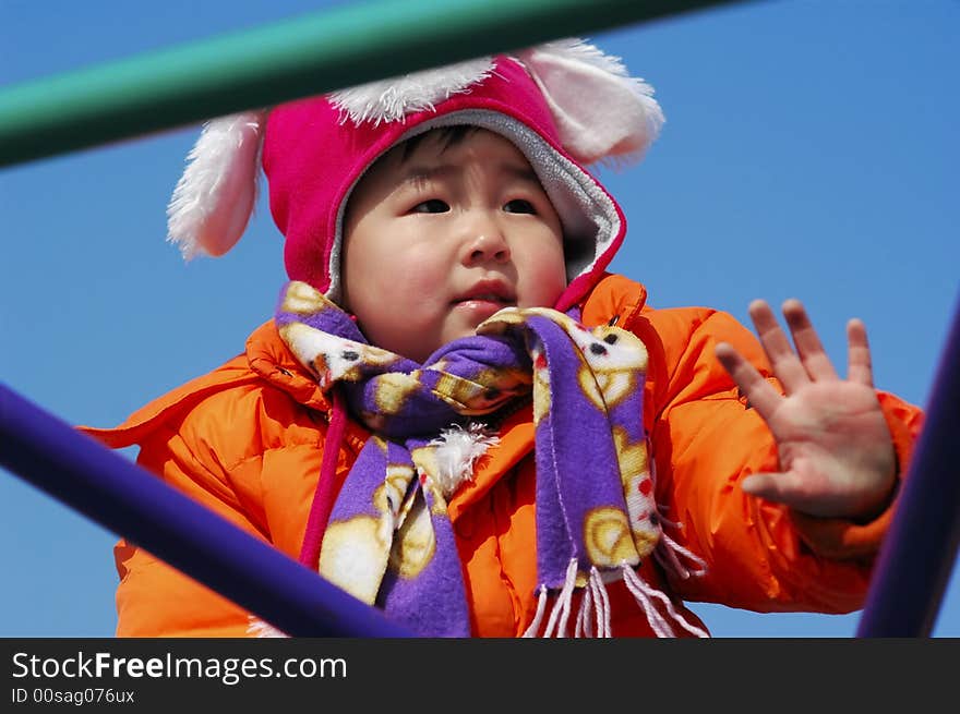 An Chinese little girl playing on climbing frame in winter