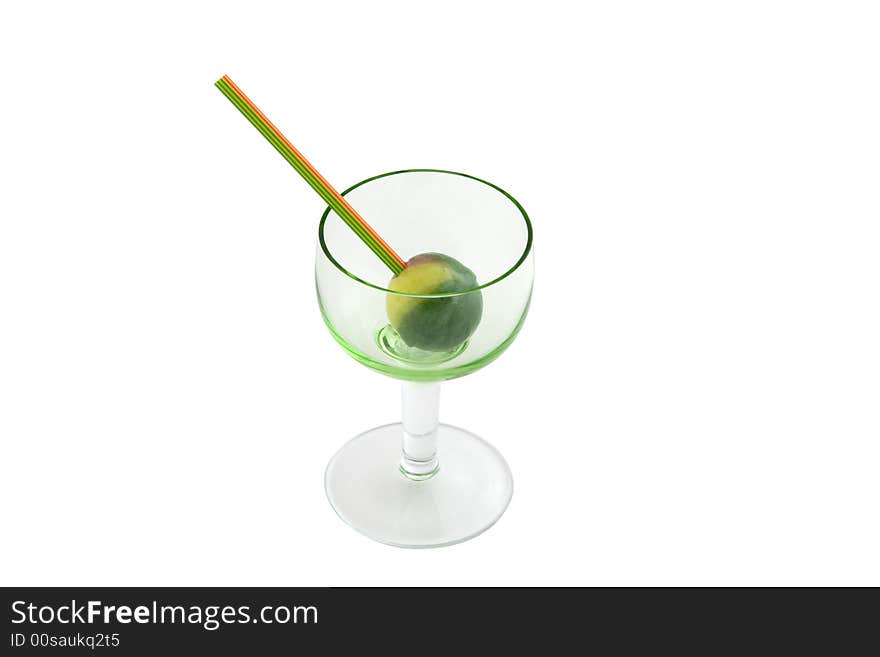 Round green and yellow bonbon with stick inside glass isolated over white