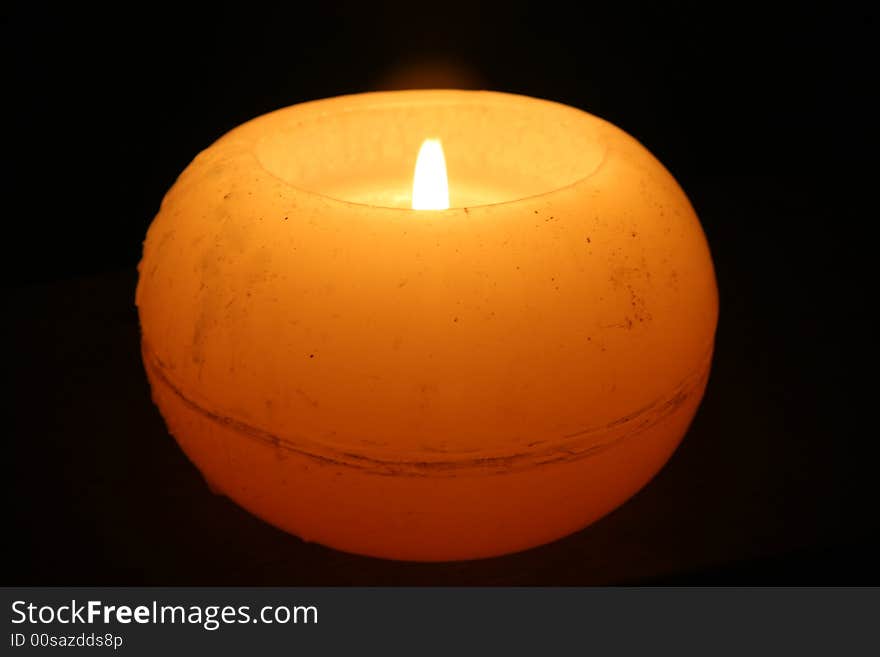 One yellow candle and black background. One yellow candle and black background