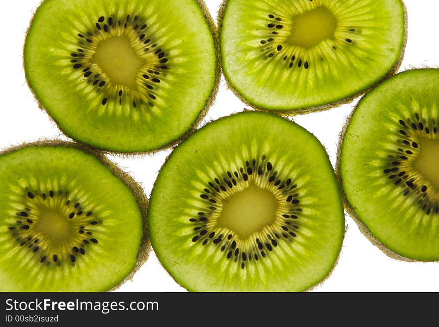 Multiple slices of Kiwi fruit, lit from behind and isolated on a white background. The color is a healthy, saturated green