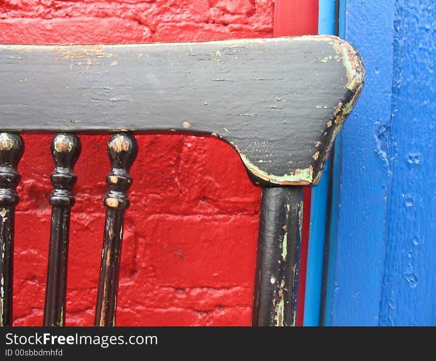 Old chair set against a brightly painted wall. Old chair set against a brightly painted wall