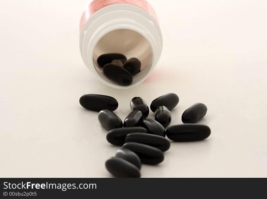 Black vitamin pills and bottle on a white background. Black vitamin pills and bottle on a white background