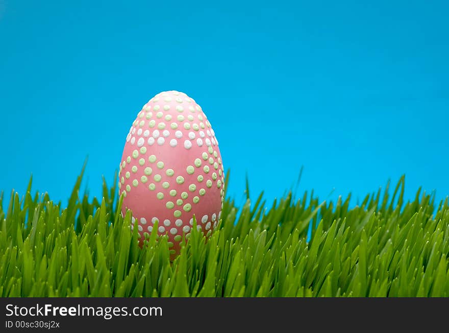 An image of a pastel easter egg in lush grass