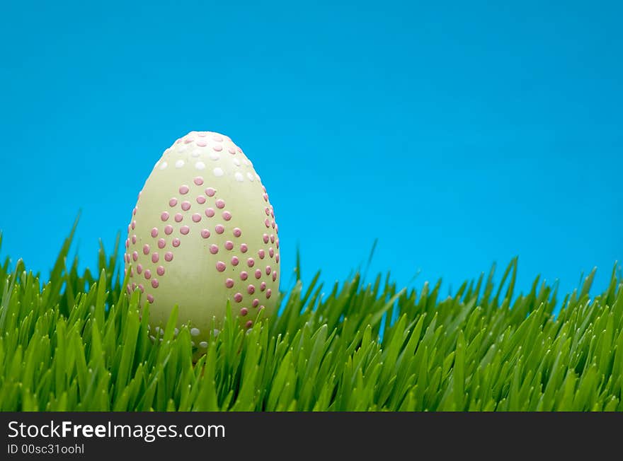 An image of a pastel easter egg in lush grass