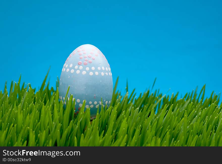 An image of a pastel easter egg in lush grass