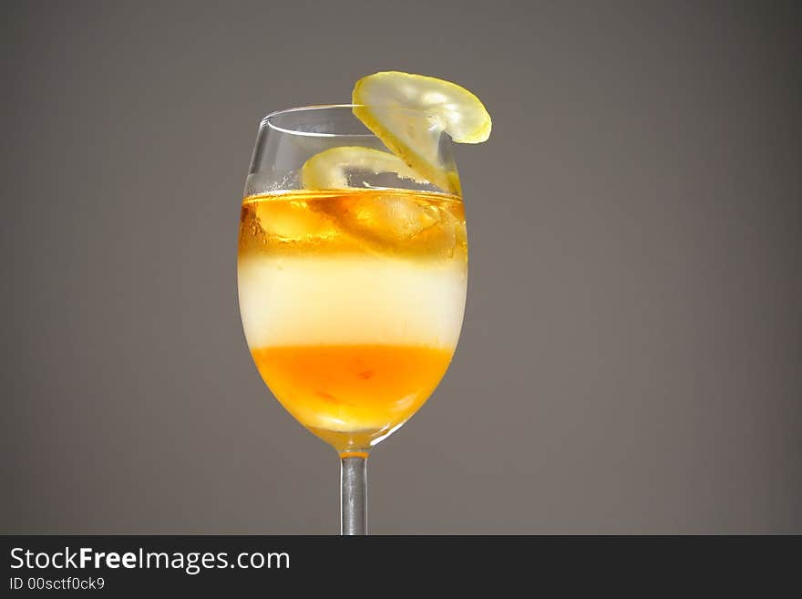 Triple layered drink with spiral lemon slice in studio light