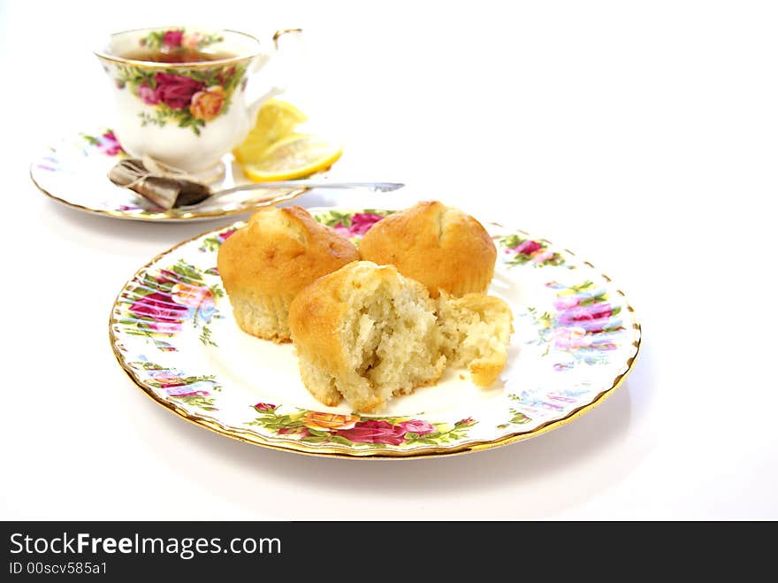 Three cake muffins on beautiful plate with cup of tea in the background. Three cake muffins on beautiful plate with cup of tea in the background