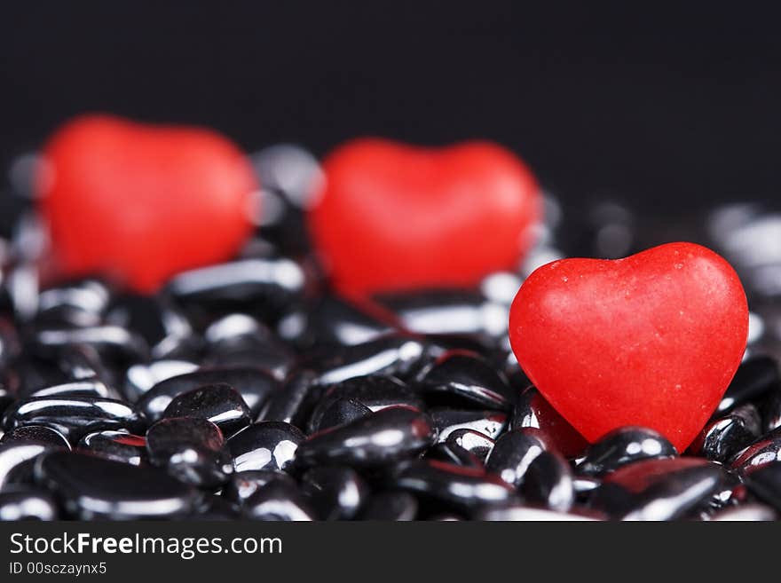 Red candy hearts on shiny pebbles. Red candy hearts on shiny pebbles