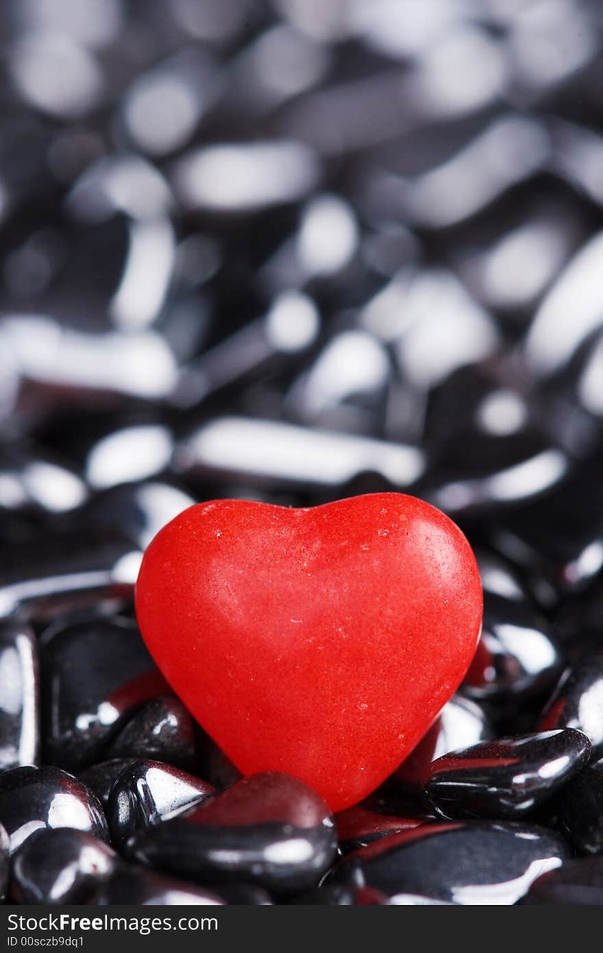 Red candy heart on shiny pebbles. Red candy heart on shiny pebbles