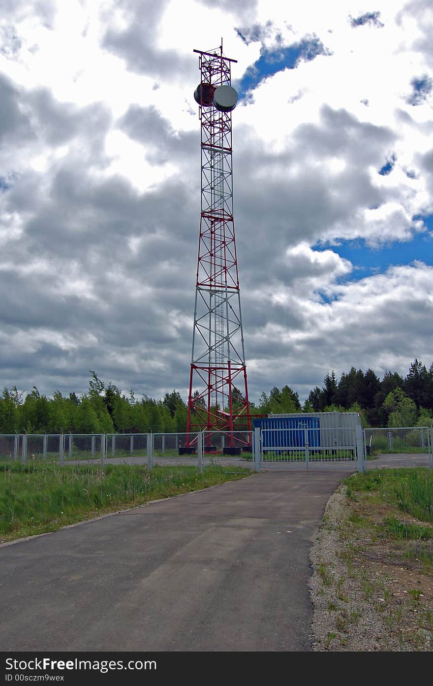 The fenced object of radiorelay communication. A tower with two aerials. Two technological containers. All object on a background of a wood and the deep cloudy sky. The fenced object of radiorelay communication. A tower with two aerials. Two technological containers. All object on a background of a wood and the deep cloudy sky.