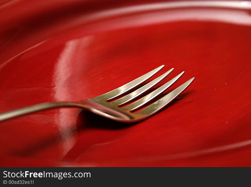 A fork on a red plate that was on my table during a recent dinner. A fork on a red plate that was on my table during a recent dinner