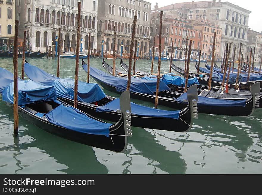 Gondolas parked in a row on canal, Venice, Veneto region, Italy. Gondolas parked in a row on canal, Venice, Veneto region, Italy.