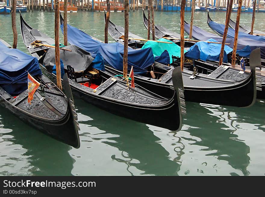 Gondolas parked in a row on canal, Venice, Veneto region, Italy. Gondolas parked in a row on canal, Venice, Veneto region, Italy.