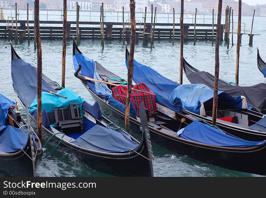 Gondolas parked in a row on canal, Venice, Veneto region, Italy. Gondolas parked in a row on canal, Venice, Veneto region, Italy.