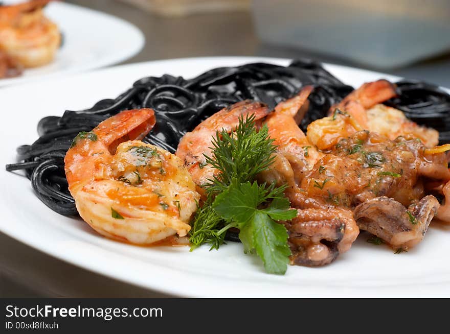 Fried shrimps with exotic black spaghetti tinted by cuttlefish ink. Fried shrimps with exotic black spaghetti tinted by cuttlefish ink