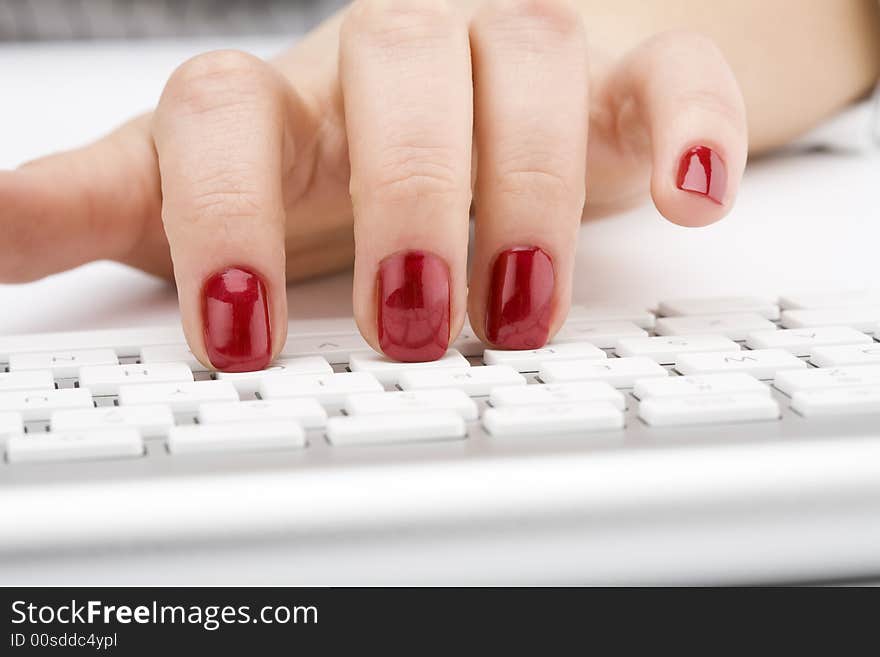 Fingers with red nail typing on keyboard