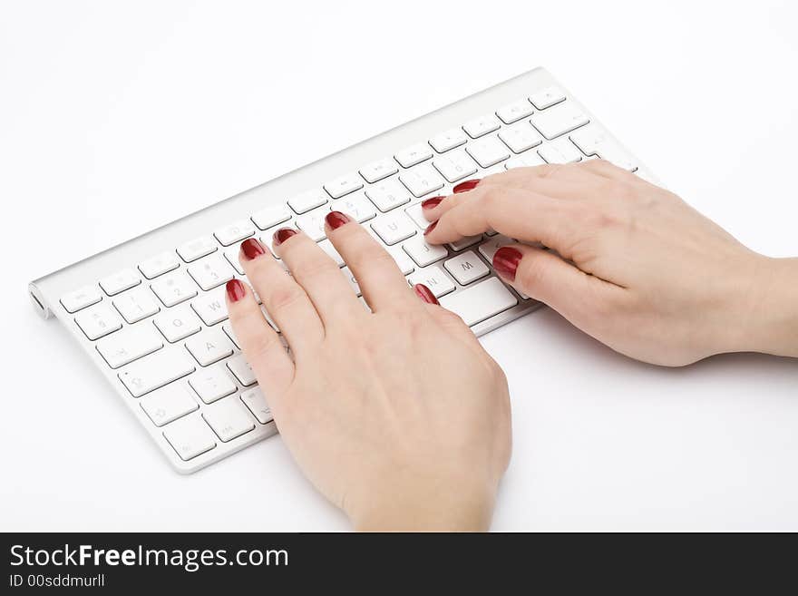 Fingers with red nail typing on keyboard