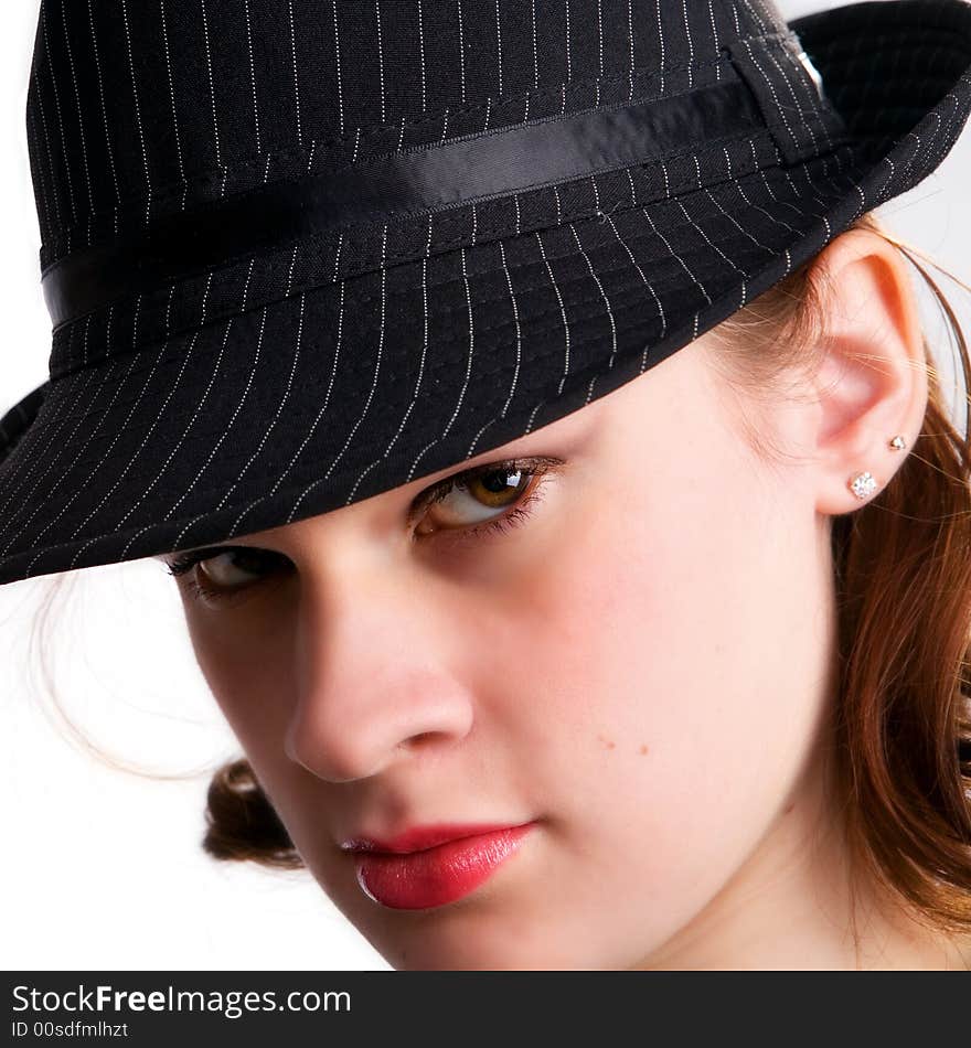 Portrait of a serios teen girl peering from under a fedora hat. Portrait of a serios teen girl peering from under a fedora hat.