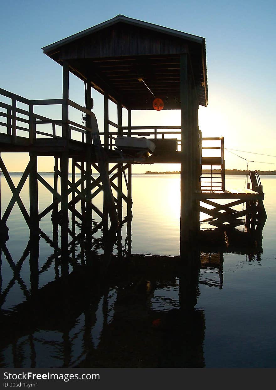 View of a dock by the ocean during sunset.