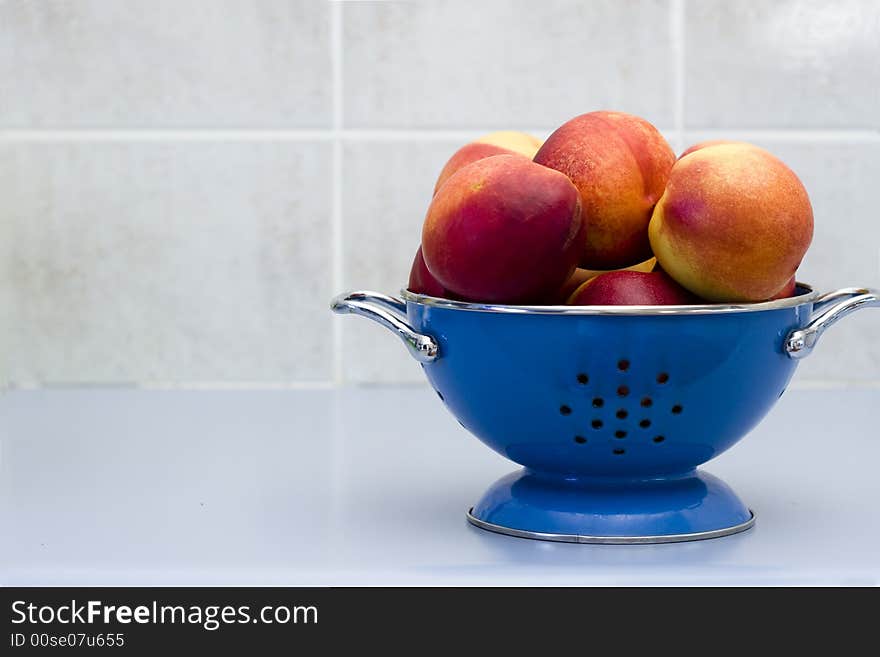 Bowl of nectarines in a blue colander